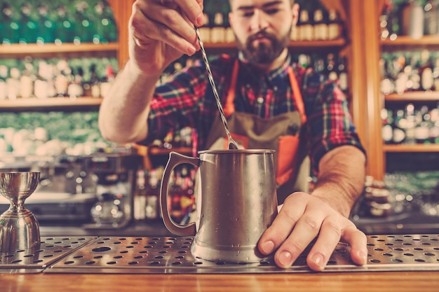 El barman haciendo un cóctel alcohólico en el mostrador del bar en el espacio del bar.