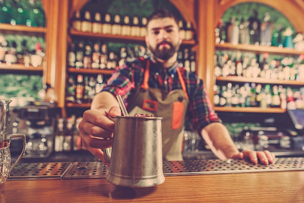 Barman haciendo un cóctel alcohólico en el mostrador del bar