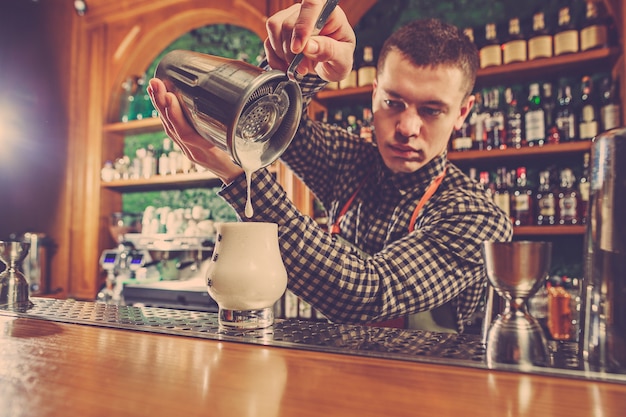 Barman haciendo un cóctel alcohólico en el mostrador del bar