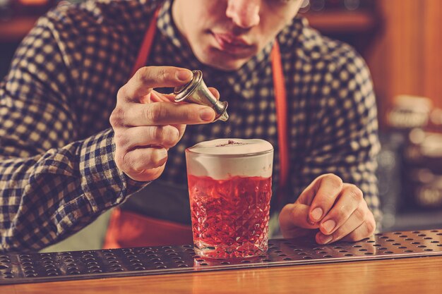 Barman haciendo un cóctel alcohólico en el mostrador del bar