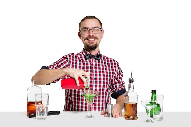 El barman masculino experto está haciendo cóctel aislado en la pared blanca. Día internacional del barman, bar, alcohol, restaurante, fiesta, pub, vida nocturna, cóctel, concepto de discoteca