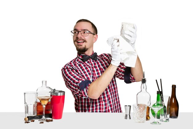 El barman masculino experto está haciendo cóctel aislado en la pared blanca. Día internacional del barman, bar, alcohol, restaurante, fiesta, pub, vida nocturna, cóctel, concepto de discoteca