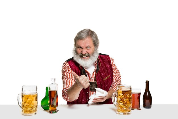 El barman masculino experto senior con cerveza en aislados en la pared blanca. Día internacional del barman, bar, alcohol, restaurante, cerveza, fiesta, pub, concepto de celebración del día de San Patricio