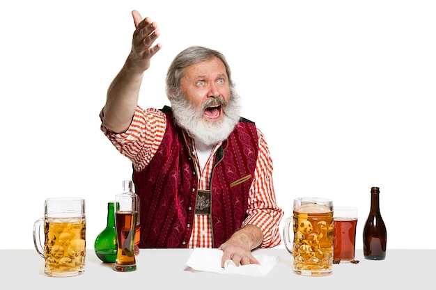 El barman masculino experto senior con cerveza en aislados en la pared blanca.