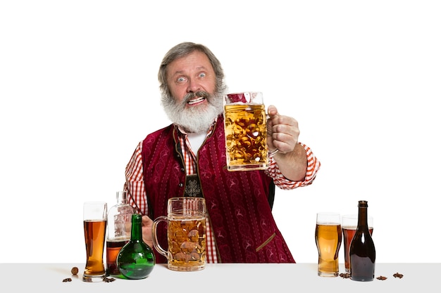 El barman masculino experto senior con cerveza en el estudio aislado en blanco