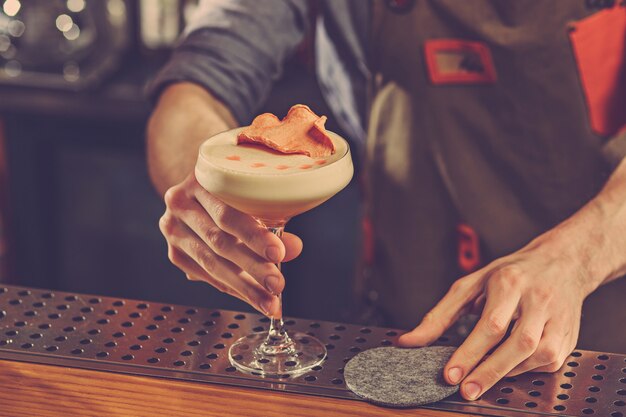Barman ofrece un cóctel alcohólico en la barra del bar