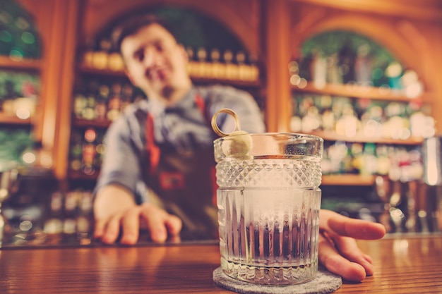 Barman ofreciendo un cóctel alcohólico en el mostrador del bar.