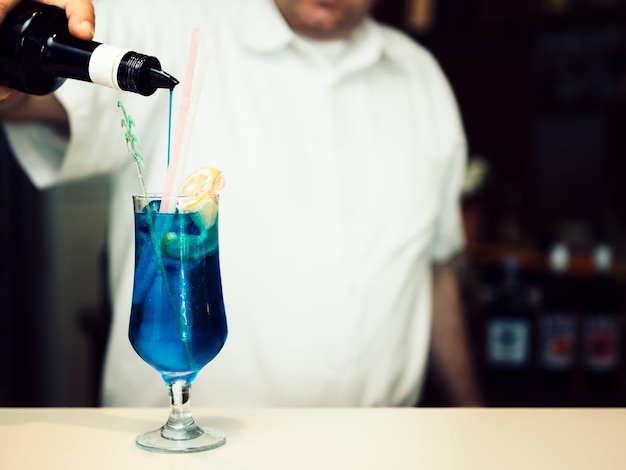 Barman relleno de vaso con bebida alcohólica azul