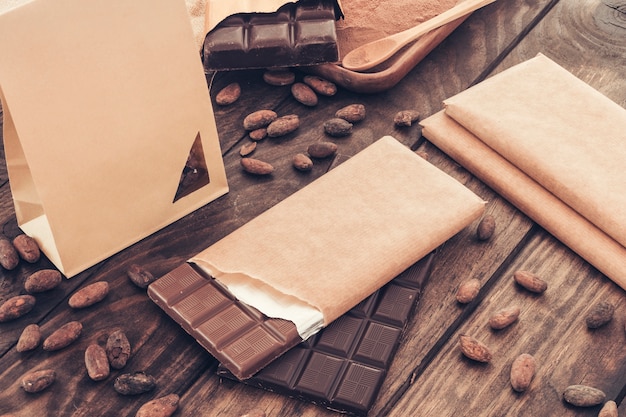 Barra de chocolate con granos de cacao en la mesa de madera