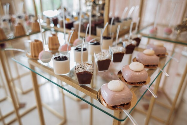 En la barra de chocolate hay moldes con porciones de postres y galletas cubiertas de crema rosa.