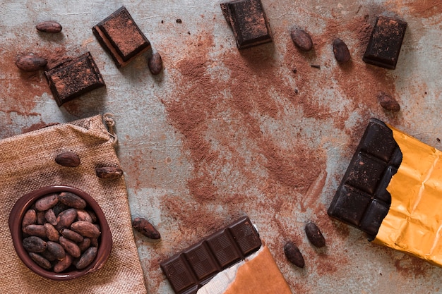 Foto gratuita barra de chocolate oscuro con cacao en polvo y frijoles dispersos