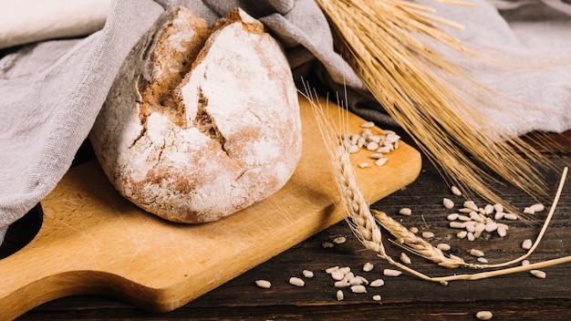 Barra de pan y espiga de trigo sobre fondo de madera oscuro