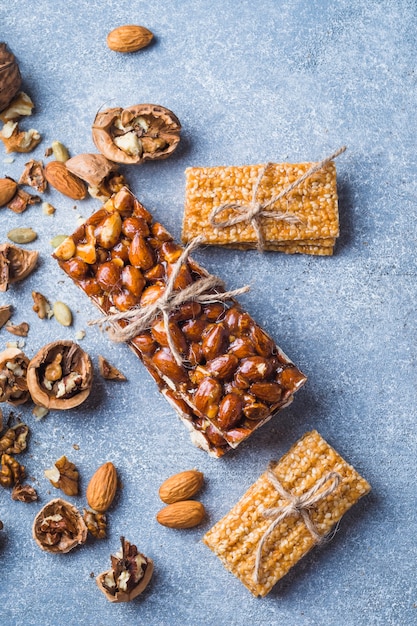 Barra saludable de sésamo y almendras atada con una cuerda sobre fondo de hormigón