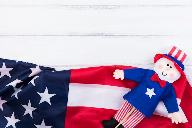 Barras y estrellas de bandera estadounidense y muñeca azul-roja sobre superficie blanca