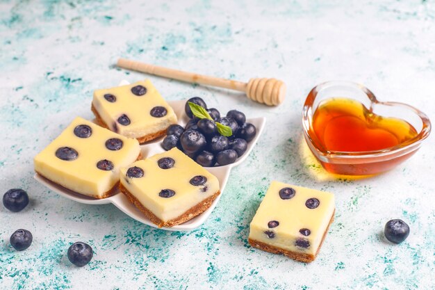 Barritas de tarta de queso de arándanos con miel y frutos rojos frescos.