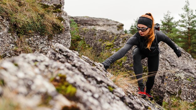 Basculador deportivo femenino escalada piedras vista frontal