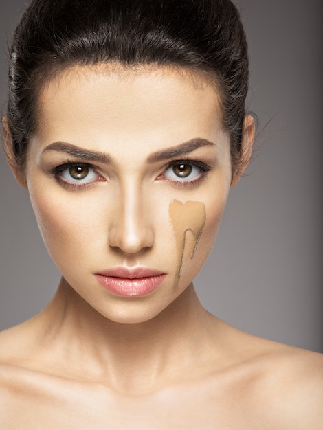 La base de maquillaje cosmético líquido está en el rostro femenino. Concepto de tratamiento de belleza. Chica hace maquillaje.