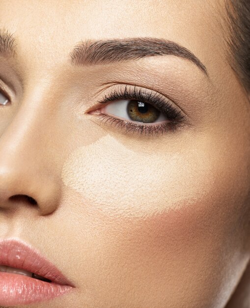 La base tonal de maquillaje cosmético está en el rostro de la mujer. Concepto de cuidado de la piel.