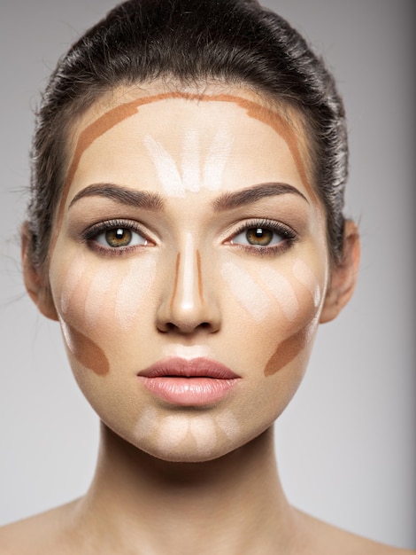 La base tonal de maquillaje cosmético está en el rostro de la mujer. Concepto de tratamiento de belleza. Chica hace maquillaje.