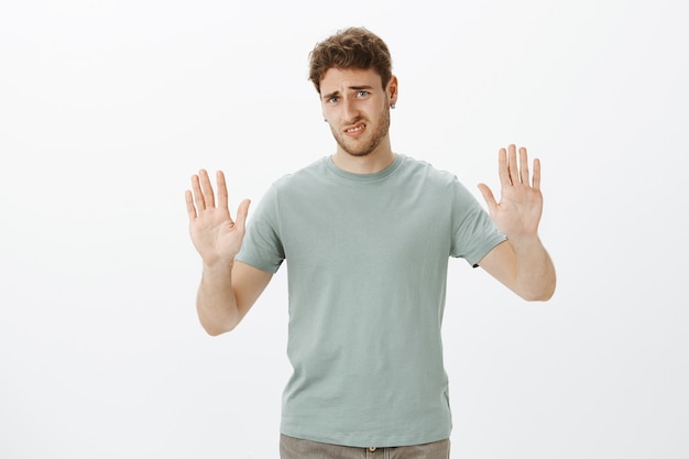 Basta, no me molestes. Hombre encantador disgustado y disgustado en camiseta, tirando de las manos hacia en gesto de rechazo