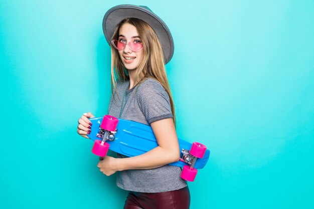 Bastante adolescente skategirl se encuentra con patineta de colores aislado sobre fondo verde