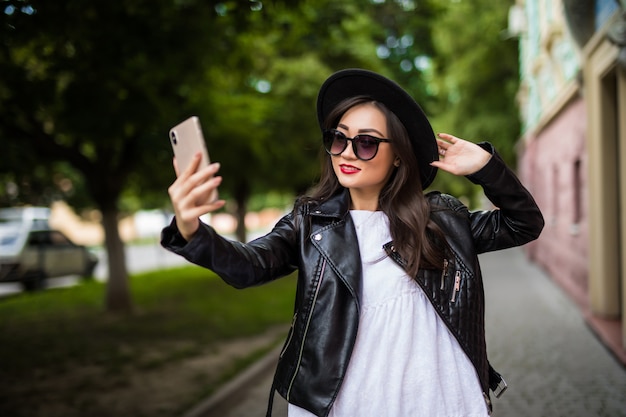 Bastante hermosa mujer asiática sonriente tomando selfie en calle de la ciudad