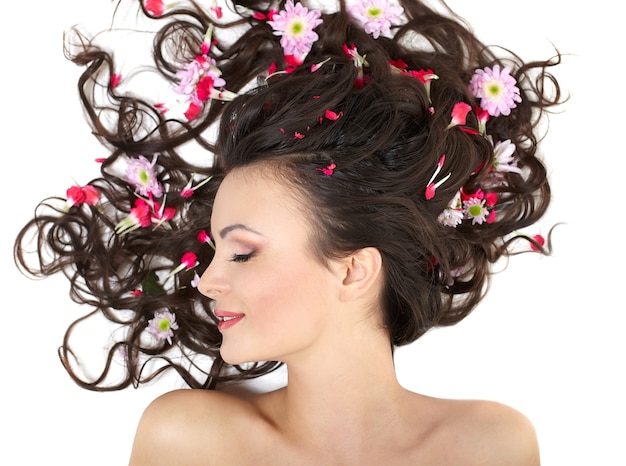 Bastante hermosa niña acostada con flores rojas brillantes en su cabello maquillaje brillante aislado en blanco