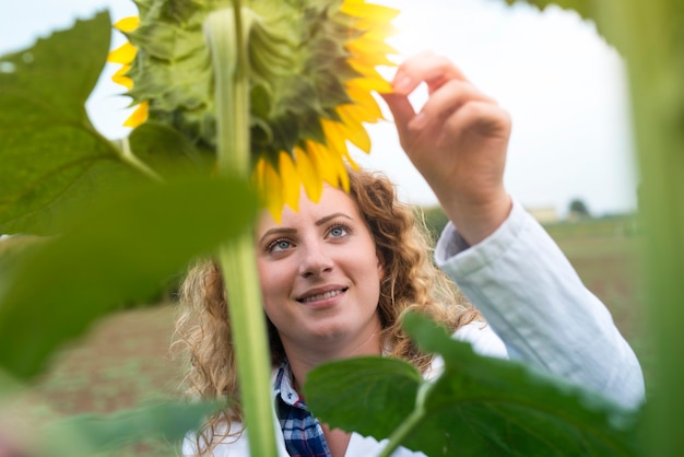 Bastante joven agrónomo experto en el campo de girasol comprobando la calidad de los cultivos