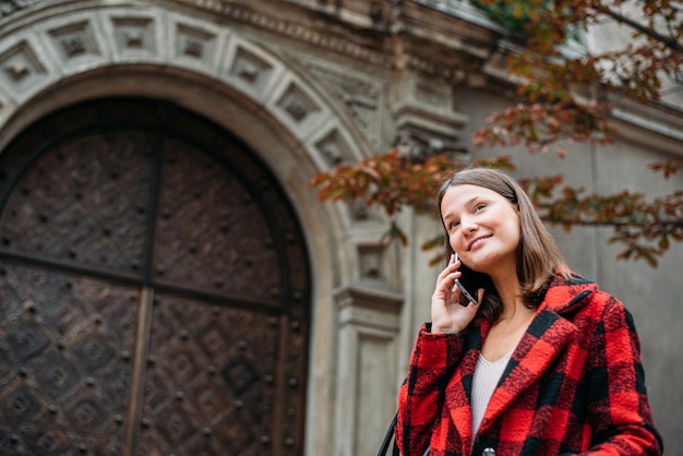 Foto gratuita bastante joven caminando por la calle con smartphone