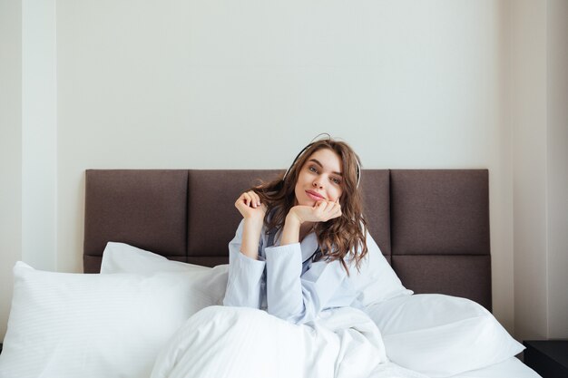 Bastante joven se encuentra en la cama en casa escuchando música.