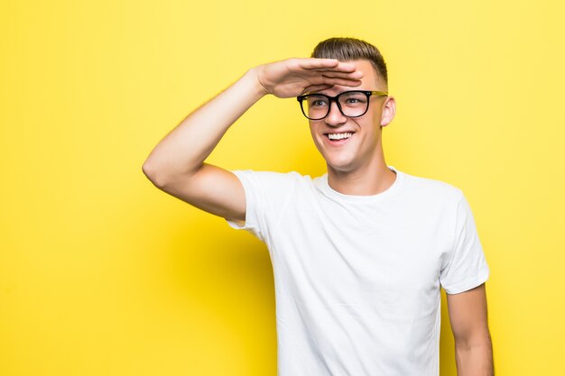 Bastante joven espera vestido con camiseta blanca y gafas transparentes aisladas en amarillo