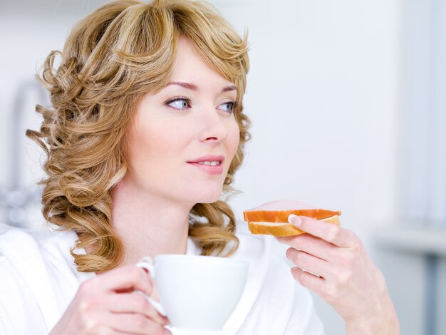 Bastante joven con hermosa sonrisa fácil desayunando en la cocina