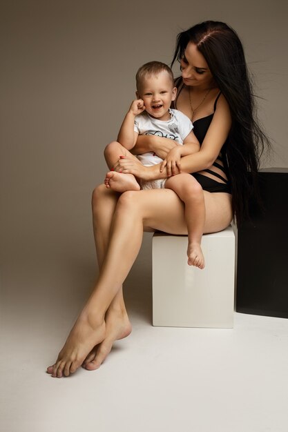Bastante joven madre amorosa en lencería con piernas desnudas abrazando a niño niño