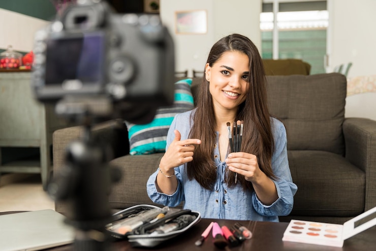 Foto gratuito bastante joven morena hablando de pinceles de maquillaje en video para su blog de belleza en línea