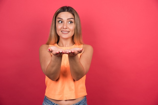 Foto gratuita bastante joven mostrando sus manos en la pared roja.