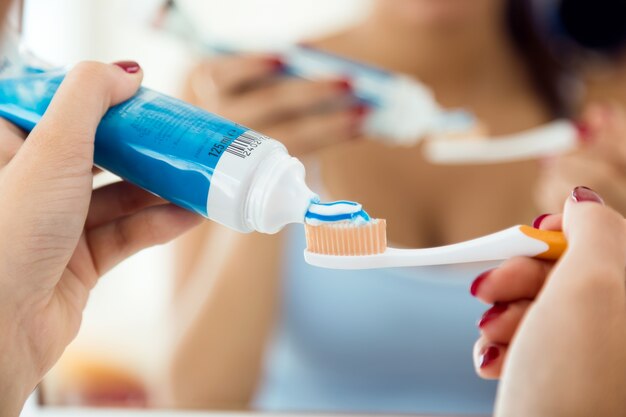 Bastante joven mujer cepillarse los dientes en el baño.