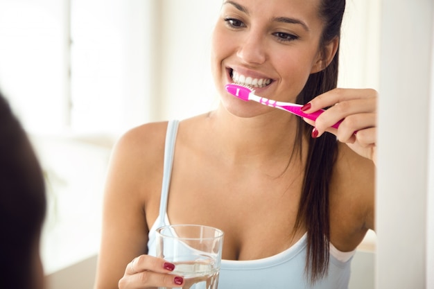 Bastante joven mujer cepillarse los dientes en el baño.