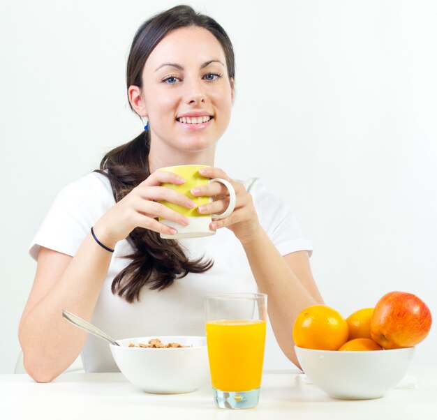 Bastante joven mujer desayunando en casa