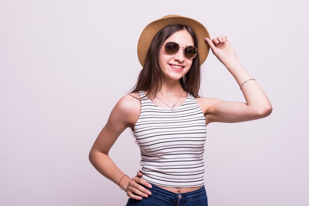 Bastante joven mujer que llevaba un sombrero, gafas de sol aislado sobre fondo blanco.