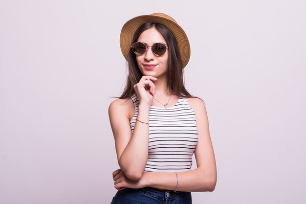 Bastante joven mujer que llevaba un sombrero, gafas de sol aislado sobre fondo blanco.