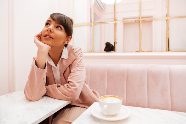 Bastante joven mujer sentada y mirando a la mesa de café