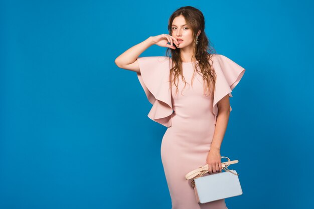 Bastante joven mujer sexy con estilo en vestido rosa de lujo, tendencia de moda de verano, estilo chic, sosteniendo el bolso de moda