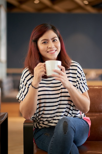 Bastante joven mujer tomando café