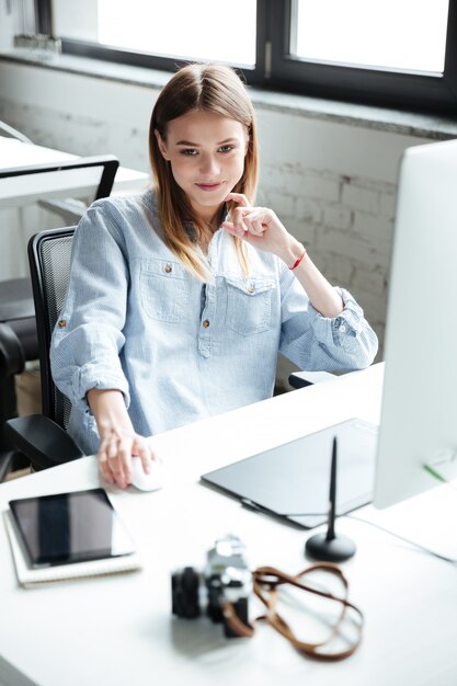 Bastante joven mujer trabaja en la oficina usando computadora