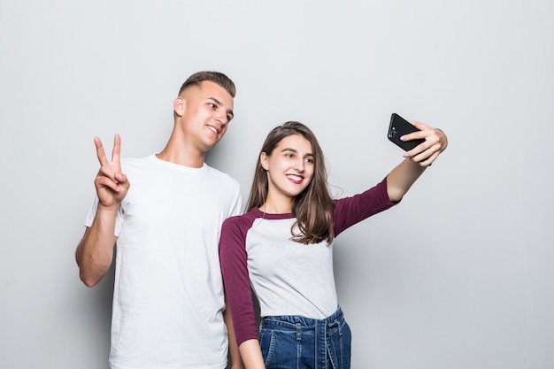 Bastante joven pareja guapo chico y chica haciendo selfie en su teléfono aislado en blanco