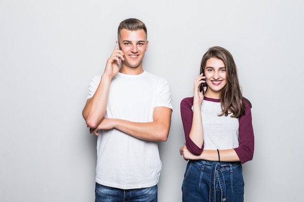 Bastante joven pareja guapo chico y chica con llamada telefónica aislado en blanco