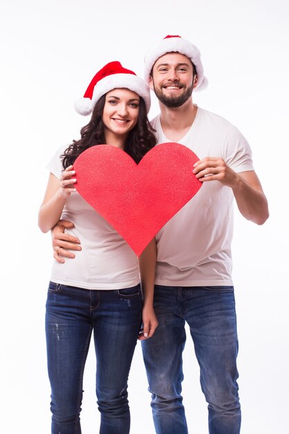 Bastante joven Santa pareja amigos hombre mujer sombrero de Navidad mantenga gran corazón en blanco vacío aislado en el estudio de fondo blanco. Feliz celebración de año nuevo feliz concepto de vacaciones