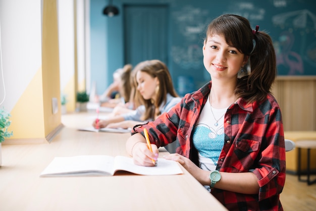 Bastante joven sentado en el escritorio en la clase