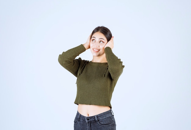 Bastante joven sosteniendo su cabeza en la pared blanca