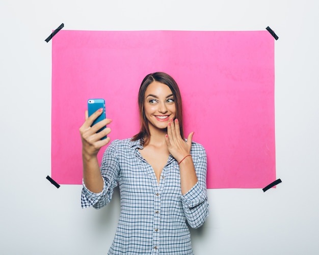 Foto gratuita bastante joven tomando foto con teléfono con cámara